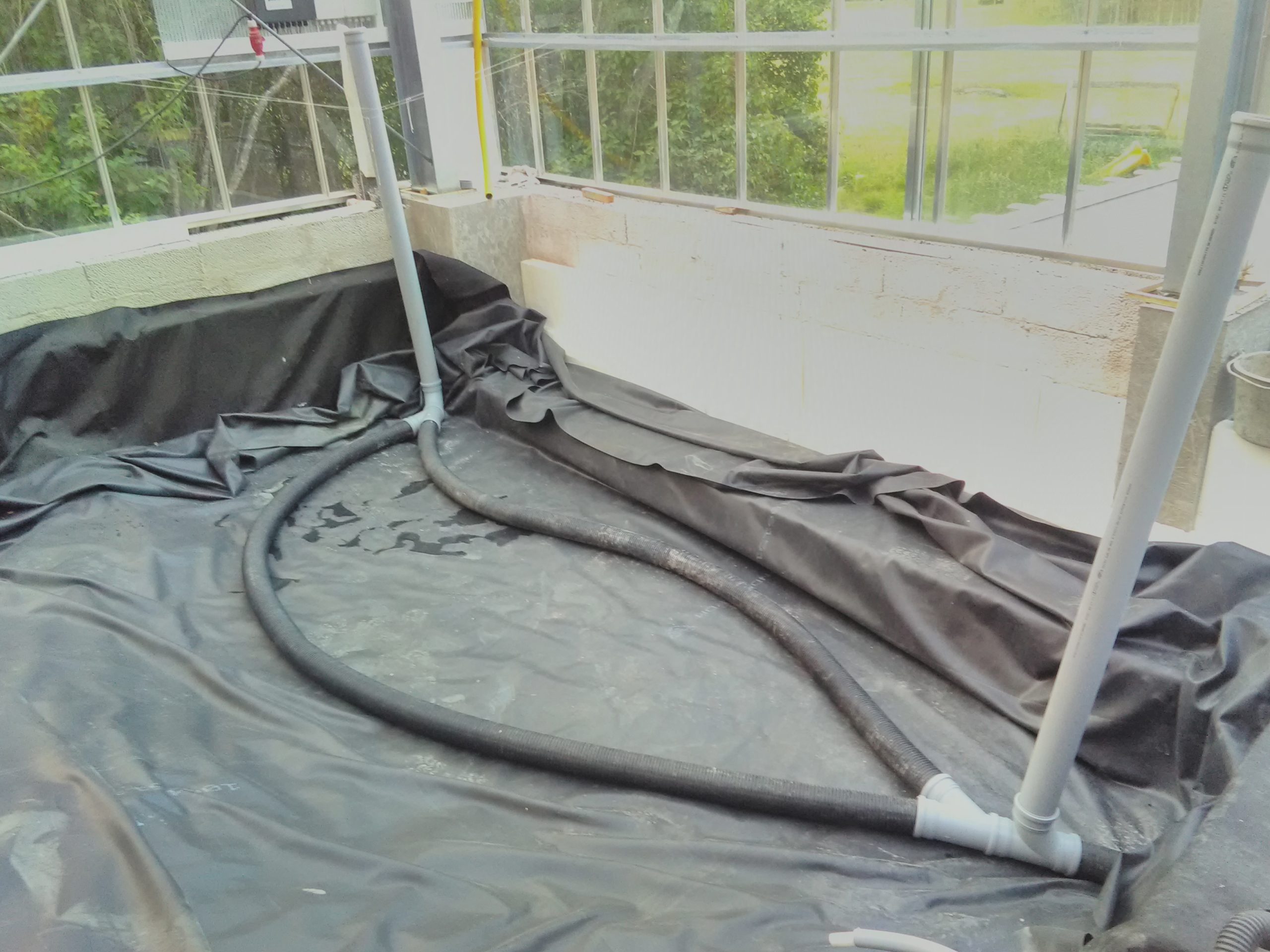 EPDM-lined growing bed with drainage pipes and protective fabric during construction of the Sundby Naturhus water-treatment system.